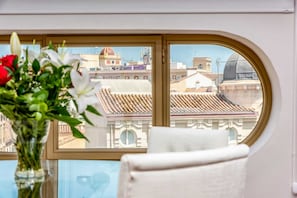 Enjoy the city view from the room's large arched window, featuring a traditional cityscape with tiled roofs and a dome.