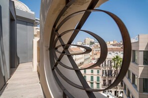 Enjoy a stylish view of the city from this balcony with a unique metal railing design, overlooking historic buildings.