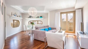 Uma sala de estar ampla com sofá, cadeiras, mesa de jantar e televisão.