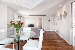 Relax in a stylish living space with a glass-top dining table, comfortable sofa, and wall-mounted mirror.