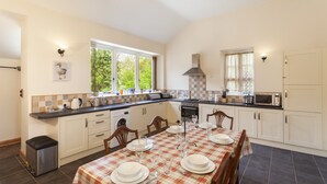 Una cocina con una mesa de comedor para seis personas, un microondas y un ventanal grande.