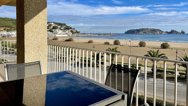 A balcony with a view of a beach, a rocky outcrop, and a distant town. - ROCAMAURA I-A-3-1 (Estartit)