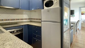 A kitchen with blue cabinets, a stainless steel stove, and a white refrigerator. - ROCAMAURA I-A-3-1 (Estartit)