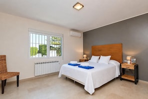 A hotel room with a bed, bedside tables, a chair, a window, and a radiator.