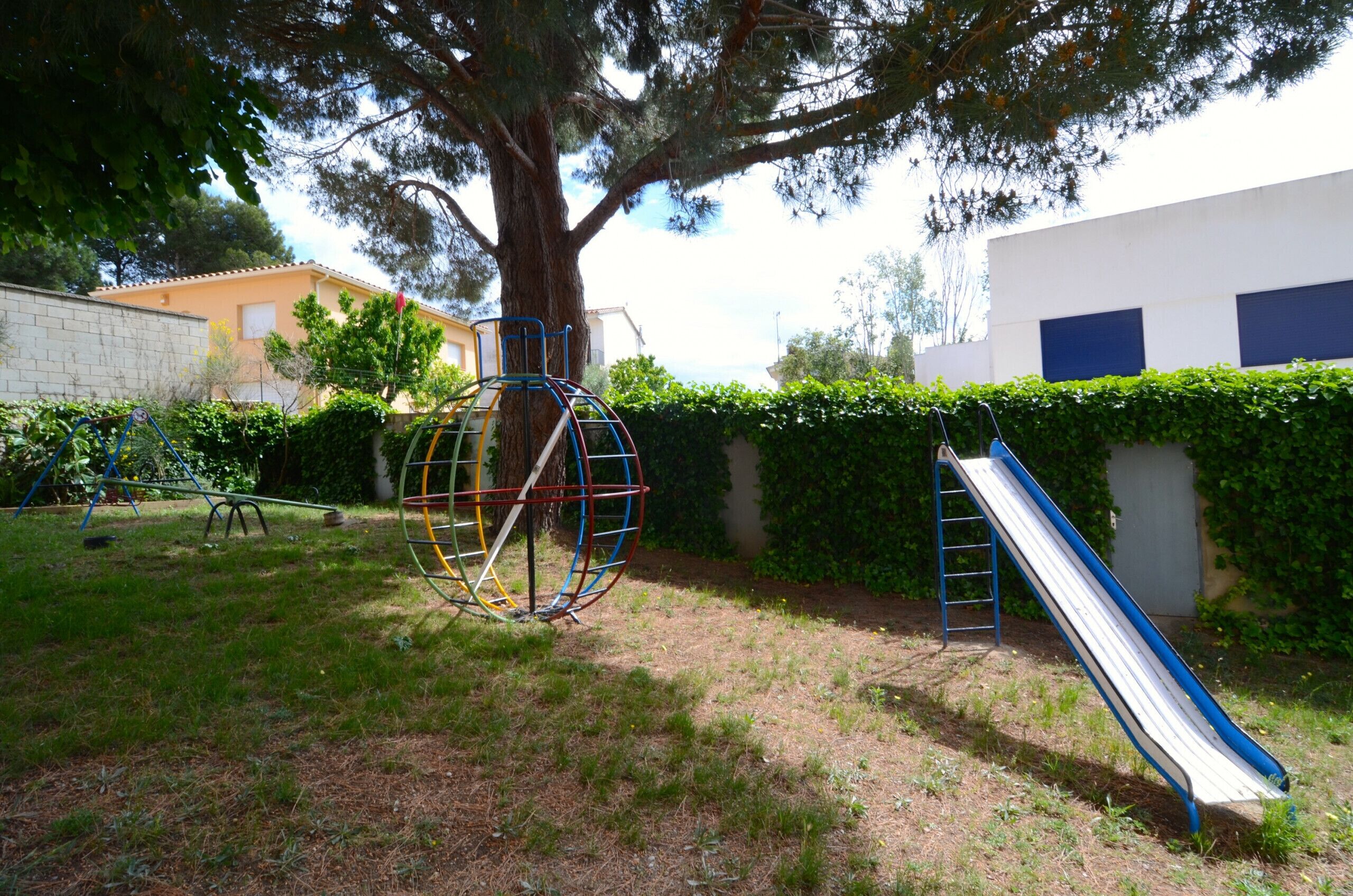 Ein Spielplatz mit Schaukel, Rutsche und Klettergerüst.