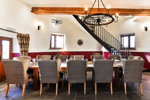 A dining area with wicker chairs, a wooden table, and a spiral staircase. - Llancayo Windmill, Near Usk , Monmouthshire, Wales (Usk)