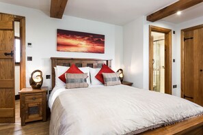 A bedroom with a large bed, wooden headboard, and a sunset painting above it.