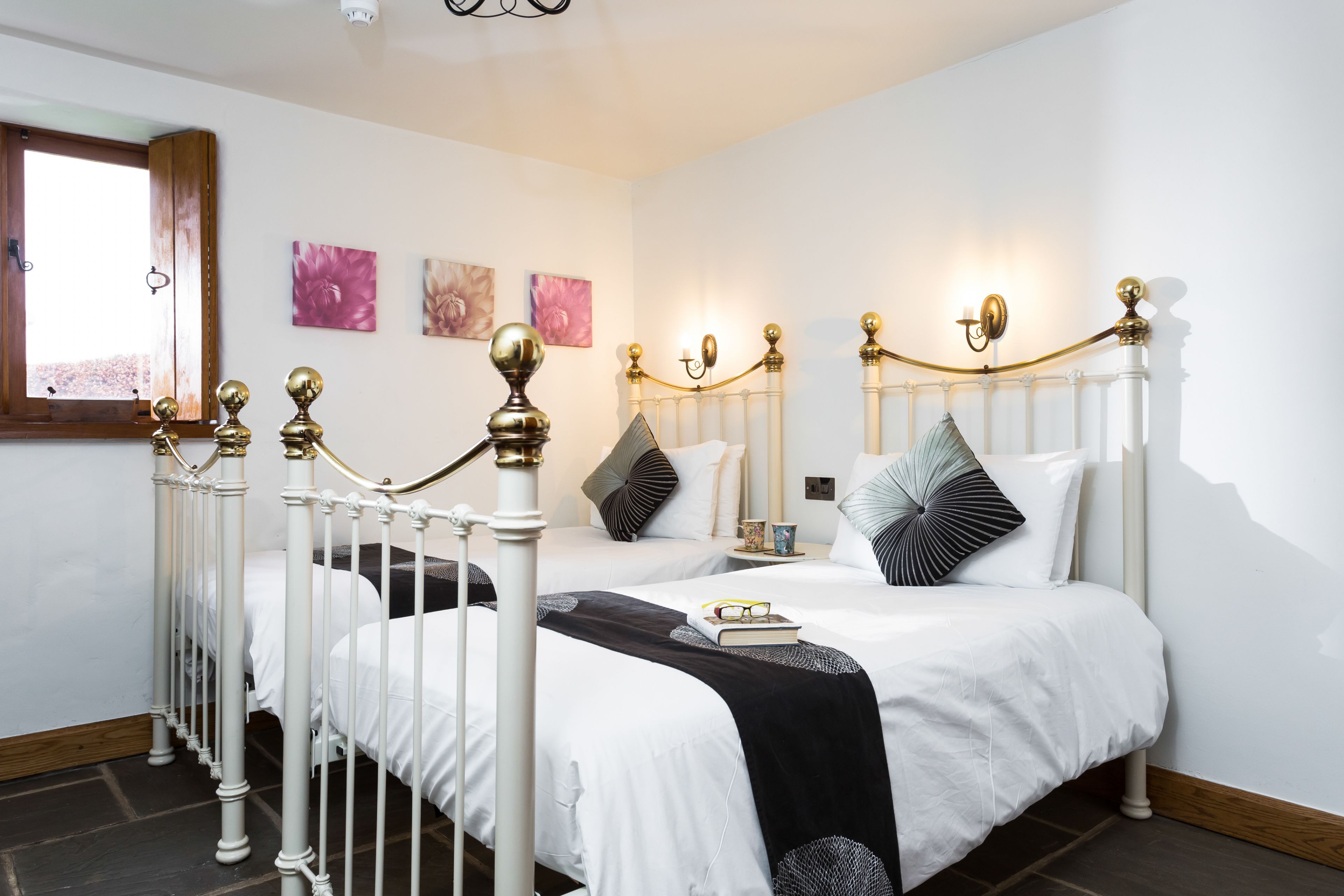 A bedroom with a white four-poster bed, a wooden floor, and a window with a view.