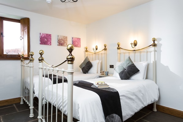 A bedroom with a white four-poster bed, a wooden floor, and a window with a view.