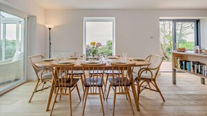 A dining area with a round table set for six, surrounded by wicker chairs.