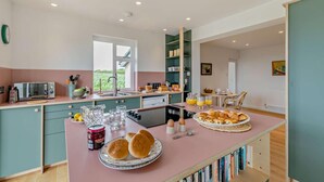 A modern kitchen with a central island, built-in appliances, and a view of greenery outside.