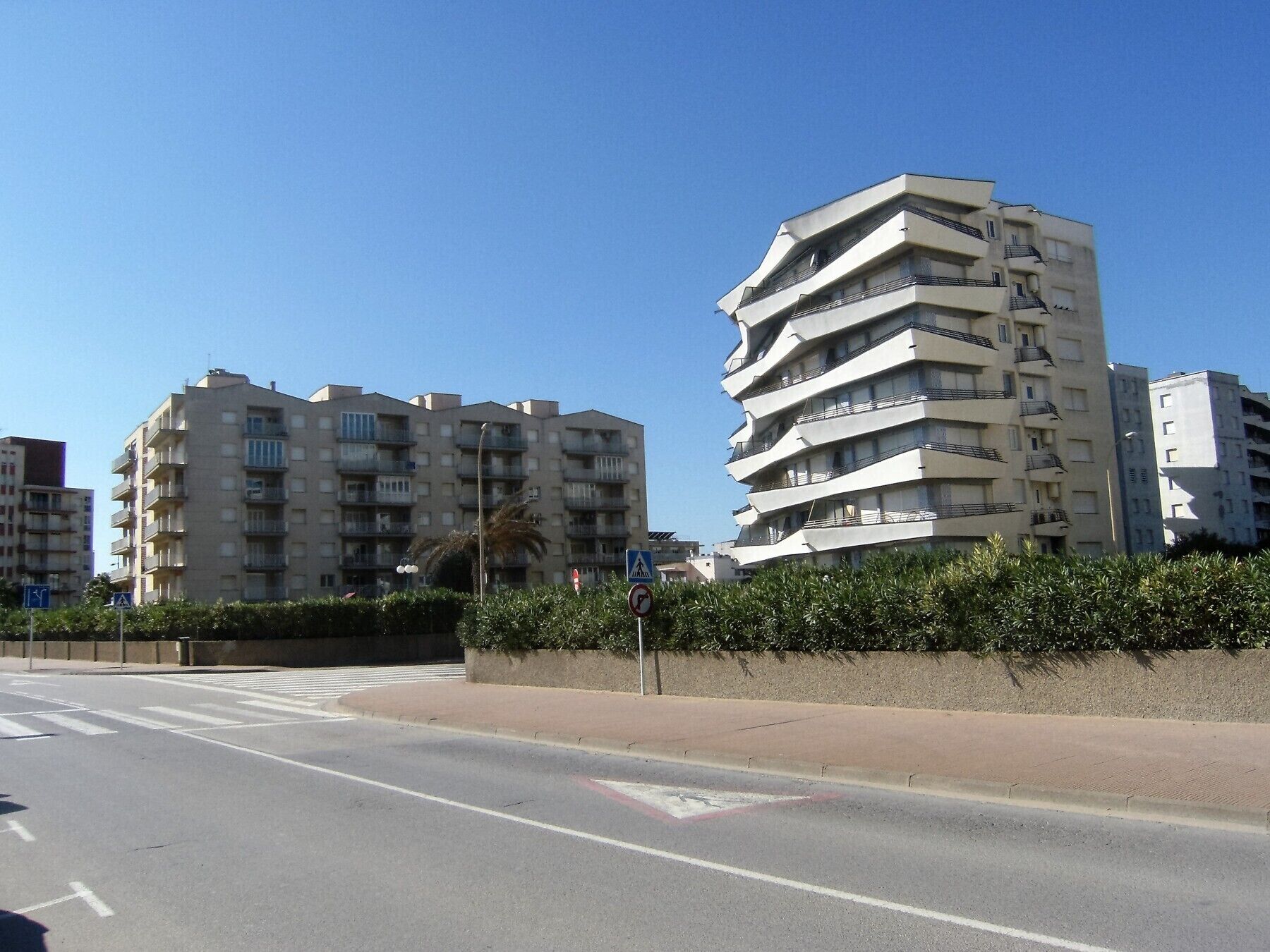 Un immeuble résidentiel à plusieurs étages, doté de balcons et d’un passage piéton.