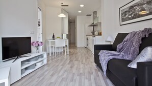 Un salon moderne avec un téléviseur à écran plat, une table à manger blanche et un canapé noir.