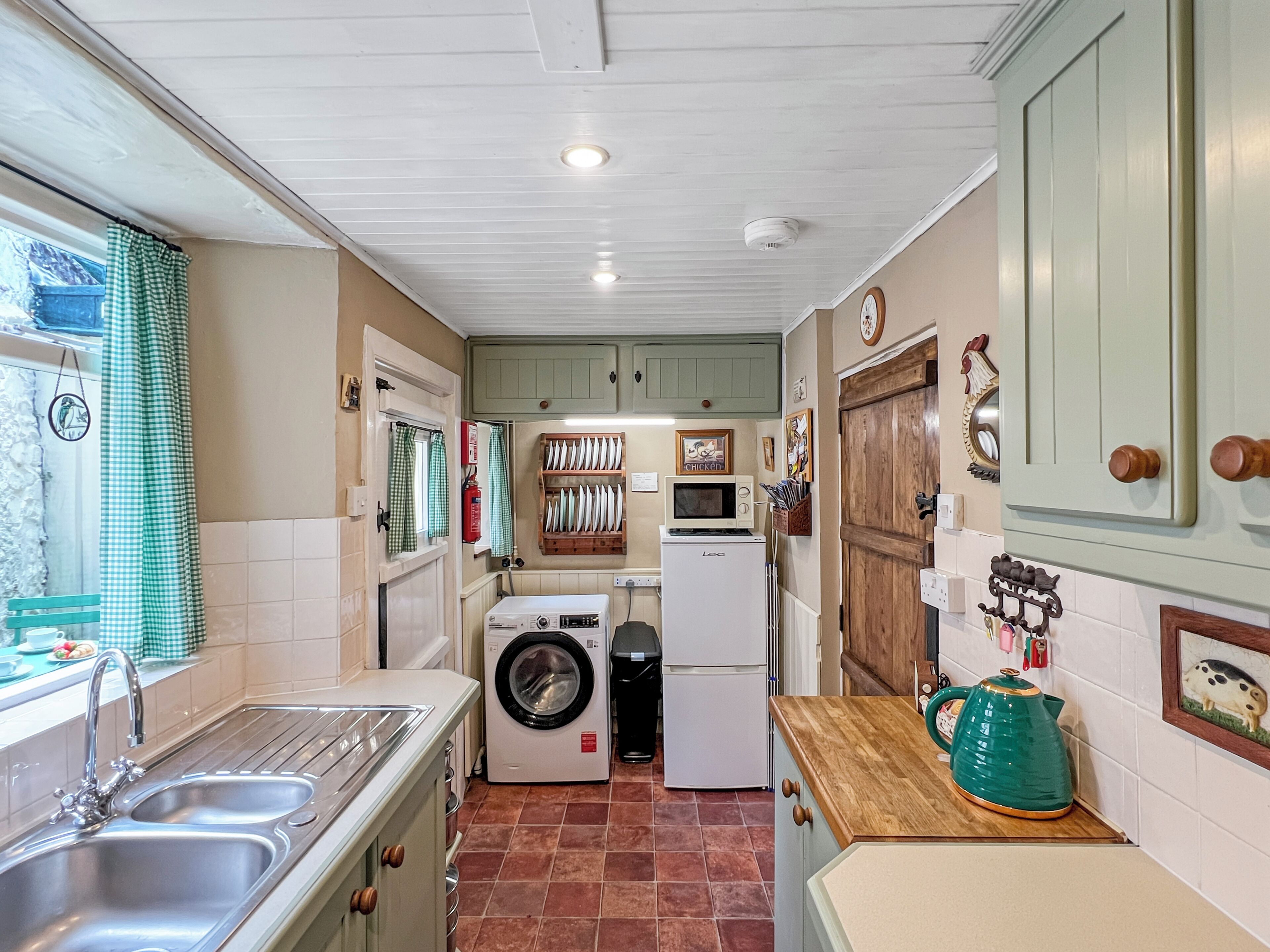 A compact kitchen with a sink, a washing machine, a microwave, and a refrigerator.