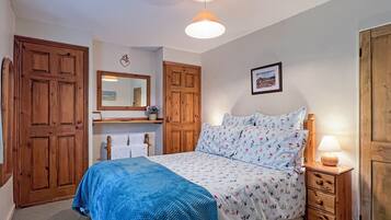 Quarto com cama, guarda-roupa de madeira, espelho, penteadeira e luminária no teto.