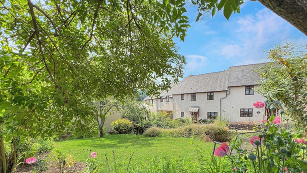 A house with a garden, surrounded by greenery and flowers.