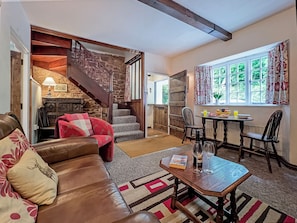 A cozy living room with a leather sofa, a wooden coffee table, and a staircase leading to another room.