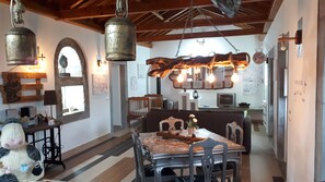 A rustic dining area with a wooden table, chairs, and a hanging light fixture. - under the bridge :) . (praia da vitoria)