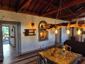A rustic interior with a wooden ceiling, a welcome sign, a table with chairs, and a hanging light fixture. - under the bridge :) . (praia da vitoria)