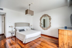 Una camera da letto con un letto, comodini, uno specchio, una cassettiera e una lampada a sospensione.
