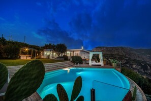 Zona piscina con vista su un paesaggio montuoso, un edificio dalla facciata bianca e un cactus sullo sfondo.