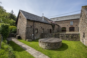 A stone building with a circular wooden deck, a stone pathway, and a small garden area. - Yenworthy Mill near Countisbury (Oare)