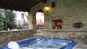 Un área al aire libre con tinaja de piedra caliente, una chimenea y un banco de piedra.