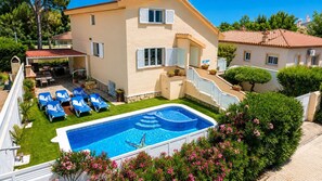 Um edifício de dois andares com piscina, área de estar externa e jardim.