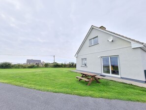 A single-story house with a patio table and a sliding glass door. - Foregloss Cottage, Ballyconneely (Ballyconneely)