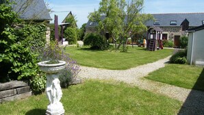 A well-maintained garden with a gravel path leading to a stone building with a sloped roof. - A 2 bedroom cottage that sleeps 4 guests  in 2 bedrooms with covered pool (Henansal)