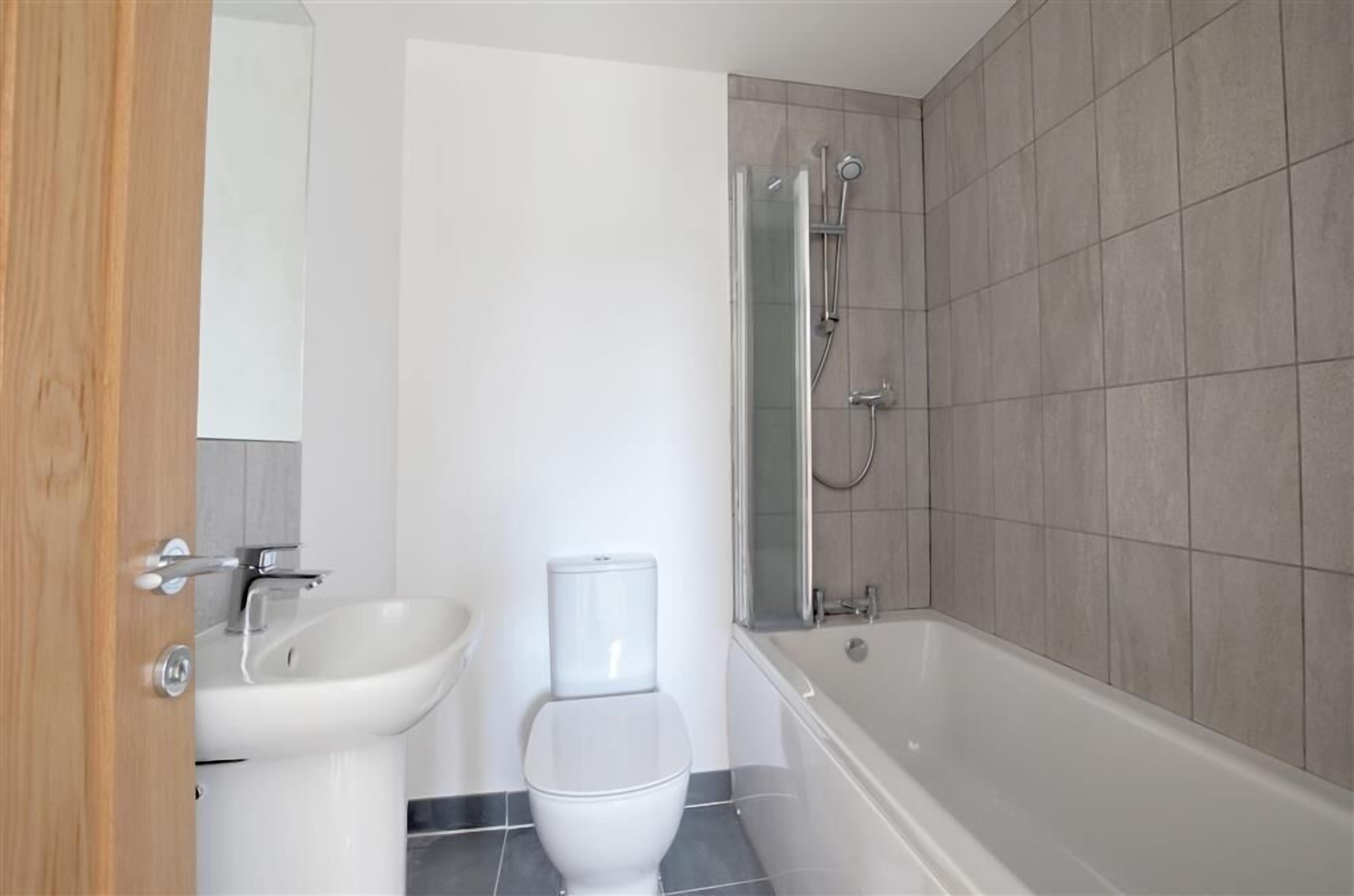 A modern bathroom with a toilet, sink, and shower.