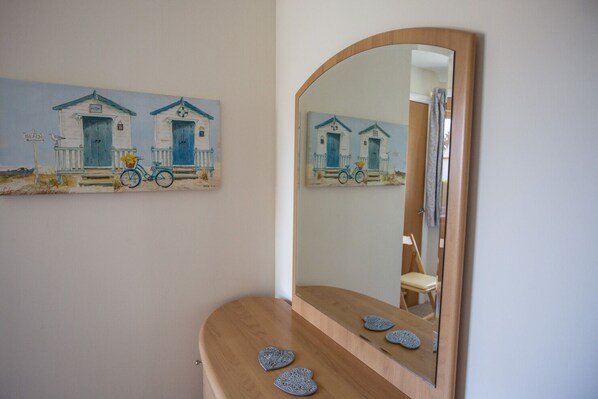 Un baño con tocador de madera, un espejo y una pintura de casas de playa.