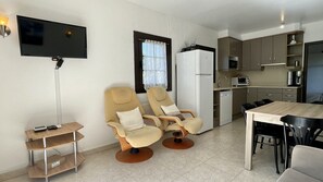 A compact kitchen with a dining table, two armchairs, a TV, and a refrigerator. - APARTAMENTO VOLENDAM - GROUND FLOOR WITH PRIVATE POOL (Estartit)