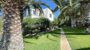 A well-maintained garden with a pathway leading to a white building with balconies.