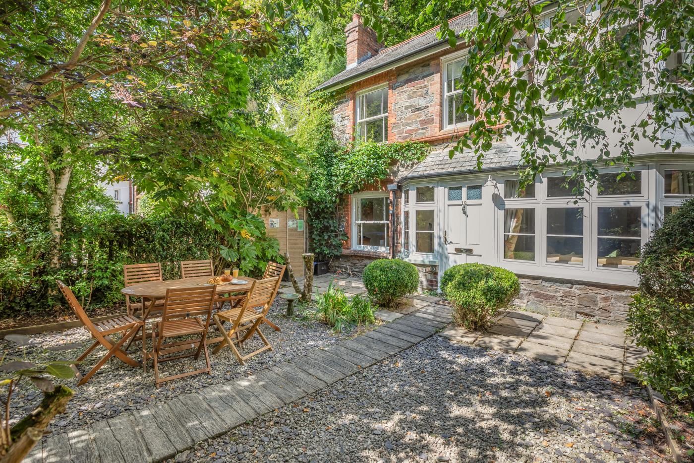 A stone house with a wooden deck and a dining area with a table and chairs.