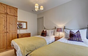A bedroom with two beds, wooden wardrobe, bedside tables, and a mirror. - 3 Bed in Lynmouth (oc-summer) (Lynmouth)