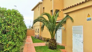 Edifici residencial amb un camí pavimentat, una bicicleta i una palmera.
