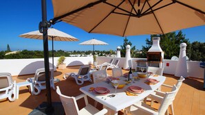 An outdoor patio with white chairs, a table set for dining, and a barbecue grill. - Townhouse Mia, Panoramic views, Communal Pool (Carvoeiro)