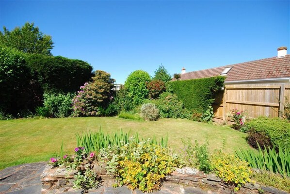 A well-maintained garden with a variety of plants and a stone border in the foreground.