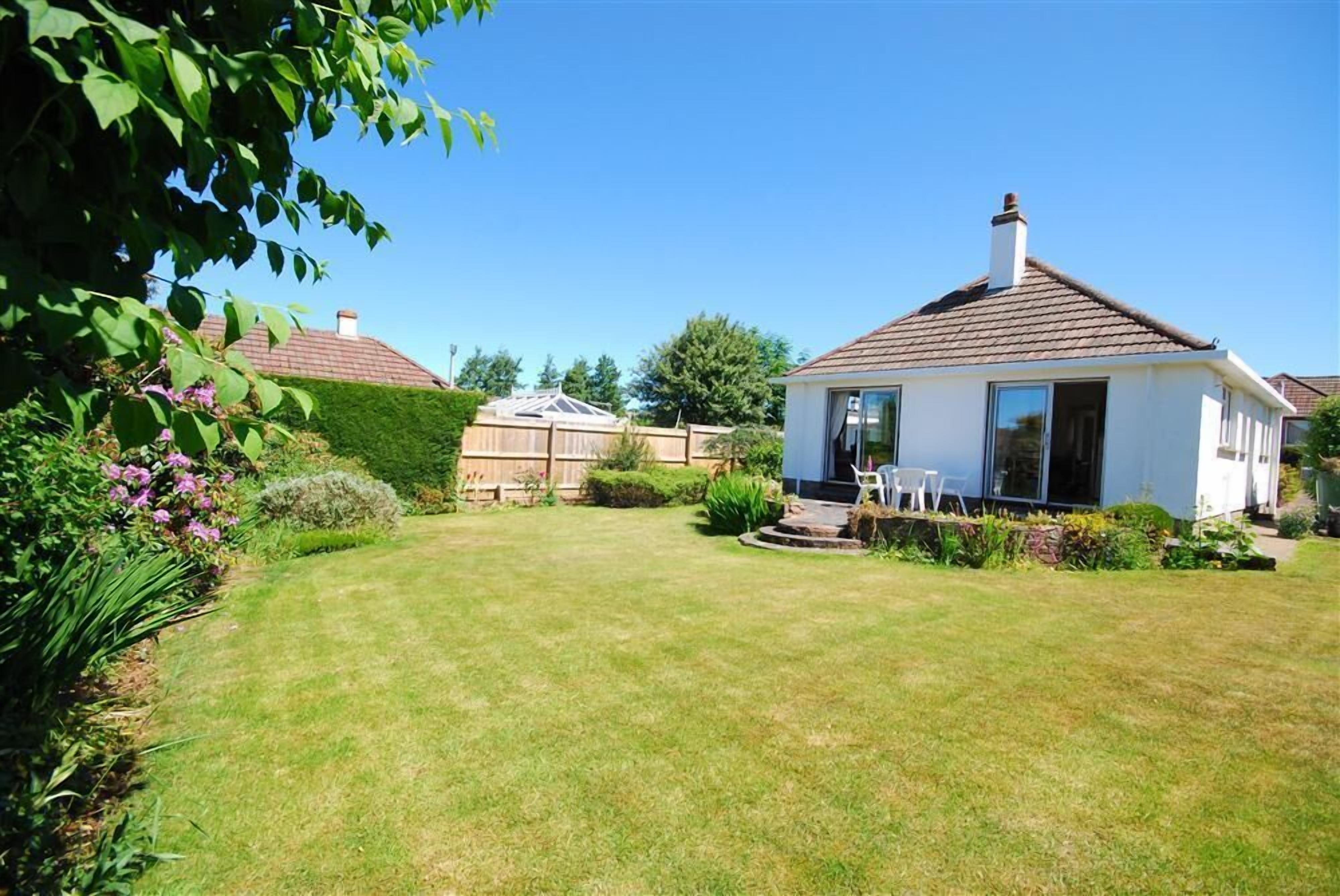 A house with a well-maintained lawn and a patio area with outdoor furniture.