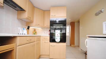 Een magnetron, een broodrooster, kookgerei, borden en bestek, eettafels