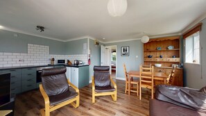 A modern kitchen with a dining area, wooden furniture, and a view into another room.
