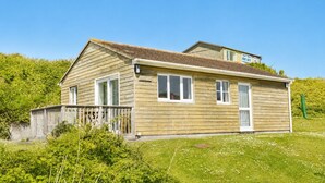 A wooden house with a sloped roof, a front porch, and a small deck. - D59 Estuary View, Riviere Towans (Hayle)
