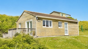 A wooden house with a sloped roof, a front porch, and a small deck.