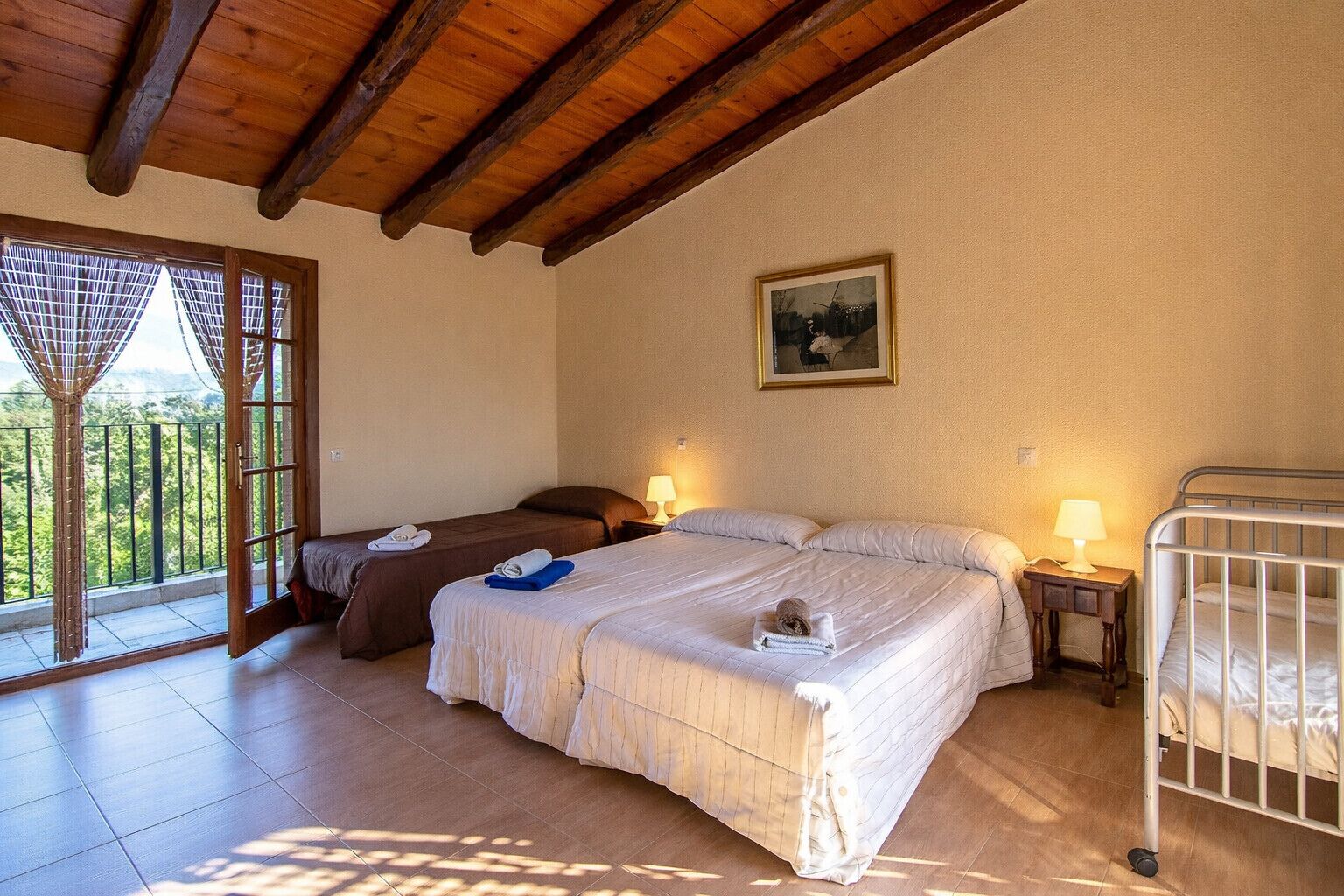 A bedroom with two beds, a balcony, and a painting on the wall.