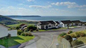 A coastal residential area with houses, a road, and a view of the sea. - 2 Bed in Woolacombe (oc-high77) (Woolacombe)