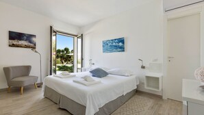 Un dormitorio moderno con cama, una silla, un escritorio y vistas al exterior.