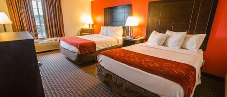 A hotel room with two beds, a desk, and a chair.