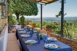 An outdoor dining area with a table set for four, surrounded by stone walls and potted plants. - Tuscany Villa with Breathtaking View at Dotholiday (Civitella in Val di Chiana)