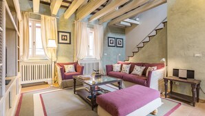 En hyggelig stue med sofaarrangement, sofabord og trappe op til en etage.